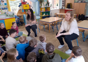 Dzieci siedzą na dywanie przed nimi nauczycielki ze Szkoły Podstawowej nr 6 opowiadają o zajęciach z Ozobotami i tabletami.