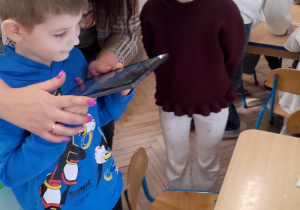 Mikołaj z pomocą pani uczy się obsługi tabletu.