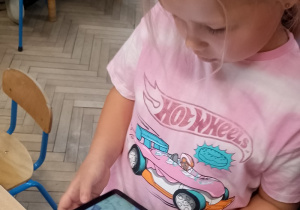 Tosia trzyma tablet na którym znajduje się królik z jej kolorowanki.