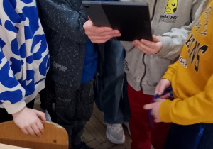 Grupa dzieci obserwuje na tablecie „ożywione” kolorowanki.