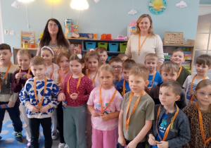 Zdjęcie grupowe przedszkolaków i nauczycielek ze Szkoły Podstawowej nr 6 z otrzymanymi upominkami: smycz na klucze i żelki.