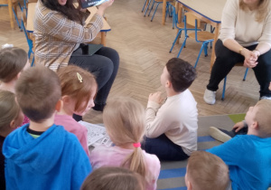 Słoneczka zgromadzone na dywanie słuchają informacji o zajęciach z tabletami.