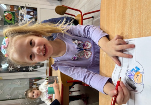 Ala uśmiecha się do zdjęcia podczas kolorowania.