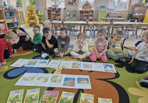 Przedszkolaki siedzą na dywanie. Przed nimi leży ułożona historyjka z przygodami Franklina oraz książki z serii "Przygody Franklina".