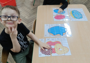 Filip i Franek układają pięcioelementowe obrazki, przedstawiające pączki.