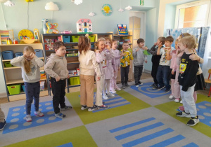 Dzieci stoją na dywanie i demonstrują jak się czują kiedy ktoś przy nich pali papierosy.