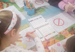 Kolejna grupka dzieci koloruje przy stole znaki "Nie pal przy mnie".
