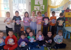 Dzieci prezentują wykonane przez siebie znaki "Nie pal przy mnie". W tle okno, tablica tematyczna z postaciami Dinka - bohatera programu "Czyste powietrze wokół nas".