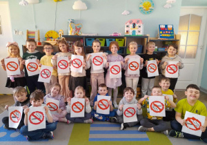 Dzieci prezentują wykonane przez siebie znaki "Zakaz palenia". W tle szafki z układankami.