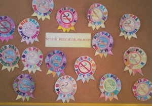 Na tablicy powieszone są prace dzieci - znaki "Nie pal przy mnie" oraz napis "Nie pal przy mnie, proszę!".