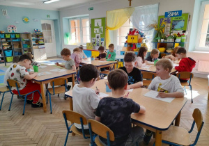 Dzieci rysują obrazki do opowiadania "O kominie który przestał dymić". W tle okna, kąciki zainteresowań.