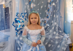 Tosia w stroju Elzy pozuje do zdjęcia na tle dekoracji.