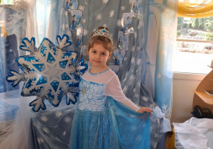 Nadia w stroju Elzy pozuje do zdjęcia na tle dekoracji trzymając balon w kształcie śnieżynki.