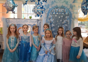 Zdjęcie grupowe dziewczynek w strojach Elzy na tle dekoracji.