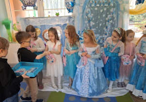 Mikołaj i Hubert wręczają dziewczynkom notesiki z motywem "Krainy lodu".