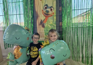 Antek i Weronika pozują do zdjęcia na tle dinozaurowej ścianki.