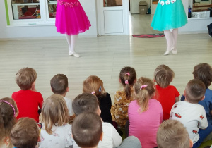 Dzieci siedzą na dywanie, a dwie tancerki prezentują "Taniec kwiatów".
