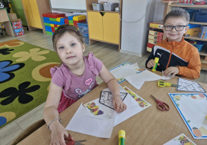 Maja i Tymuś siedzą przy stoliczku tworząc prace plastyczne.
