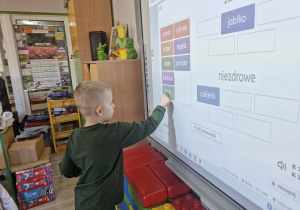 Lucjan z wykorzystaniem tablicy interaktywnej segreguje produkty spożywcze na zdrowe i niezdrowe.