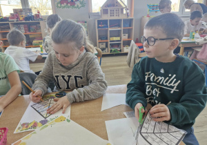 Weronika i Antoś siedzą przy stoliku w trakcie tworzenia pracy plastycznej: piramidy zdrowego żywienia.