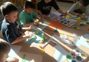 2. Dzieci malują dinozaury za pomocą umoczonych w farbie palców u rąk.