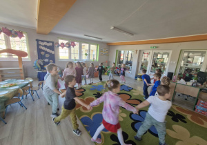 Dzieci tańczą w kółeczku trzymając się za ręce.