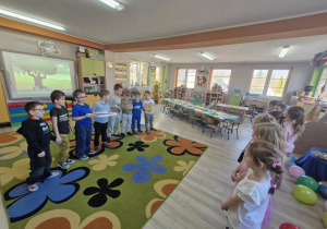 Chłopcy stoją ustawieni naprzeciwko dziewczynek i składają im życzenia.