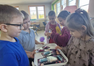 Tymuś i Wojtuś wręczają dziewczynkom upominki.