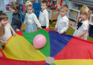 Dzieci zgromadzone wokół chusty animacyjnej, na której jest różowy balon.