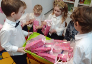 Michał i Michał trzymają tacę z upominkami i rozdają dziewczynkom prezenty.