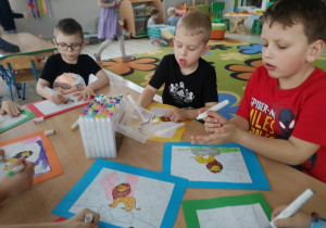 Franek, Lucjan i Antek malują mazakami lwa.