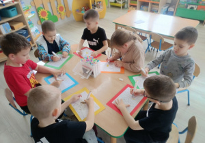 Przedszkolaki wykonują prace plastyczną - malują mazakami lwa.