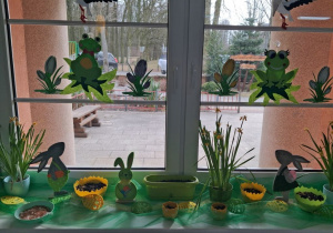 Parapet w sali, na którym stoją doniczki w kształcie połówek jajek z wysianym owsem i dekoracja wiosenno-wielkanocna.