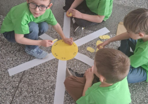 Grupka chłopców siedzi na podłodze i dopasowuje wynik odejmowania na promykach słońca.