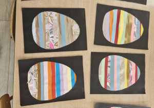 Na stoliku leża wykonanie przez dzieci prace plastyczne: wielkanocne pisanki z kolorowego papieru.