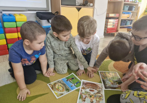 Dzieci oglądają obrazki, na których widać wielkanocne potrawy.