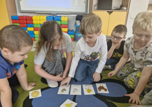 Przedszkolaki układają obrazki w kolejności zgodnej z rymowanką „Trzy kurczęta”.
