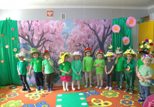 Grupa "Motylków" pozuje do zdjęcia na tle dekoracji w kapeluszach.