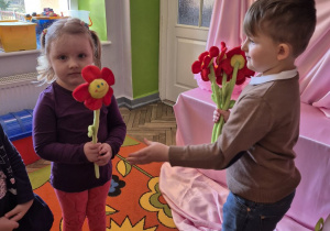 Krzyś wręcza czerwonego pluszowego kwiatka Kalinie.