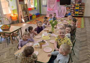 "Motylki" siedzą przy złączonych stolikach, przed każdym stoi talerzyk. Dzieci zaczęły słodki poczęstunek.
