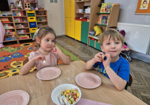 Zadowolony Józio i Jagoda w trakcie słodkiego poczęstunku siedzą przy stole.