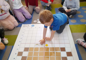 Bruno na podstawie podanego kodu układa na macie element pogody.