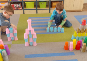 Staś i Mikołaj odwzorowują ustawione na dywanie wieże.