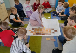 Nikola na podstawie podanych koordynatów układa na macie symbol przedstawiający słońce.