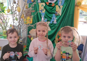 Nikola, Bartek i Wiktor pozują do zdjęcia na tle dekoracji z wykonanymi pracami.