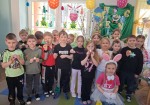 Zdjęcie grupowe na tle dekoracji z otrzymanymi upominkami.