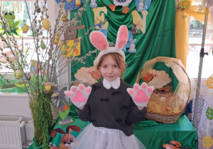 Emma w stroju zajączka pozuje do zdjęcia na tle dekoracji.