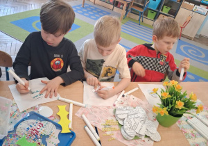 Grupka chłopców podczas malowania pisanek z pianki.