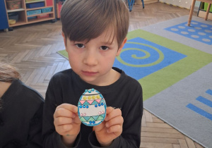 Staś prezentuje wykonaną pisankę.