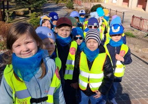 Dzieci ustawione parami na terenie przedszkola. W tle budynek przedszkola.